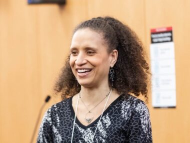 A woman speaks into a microphone at an event.