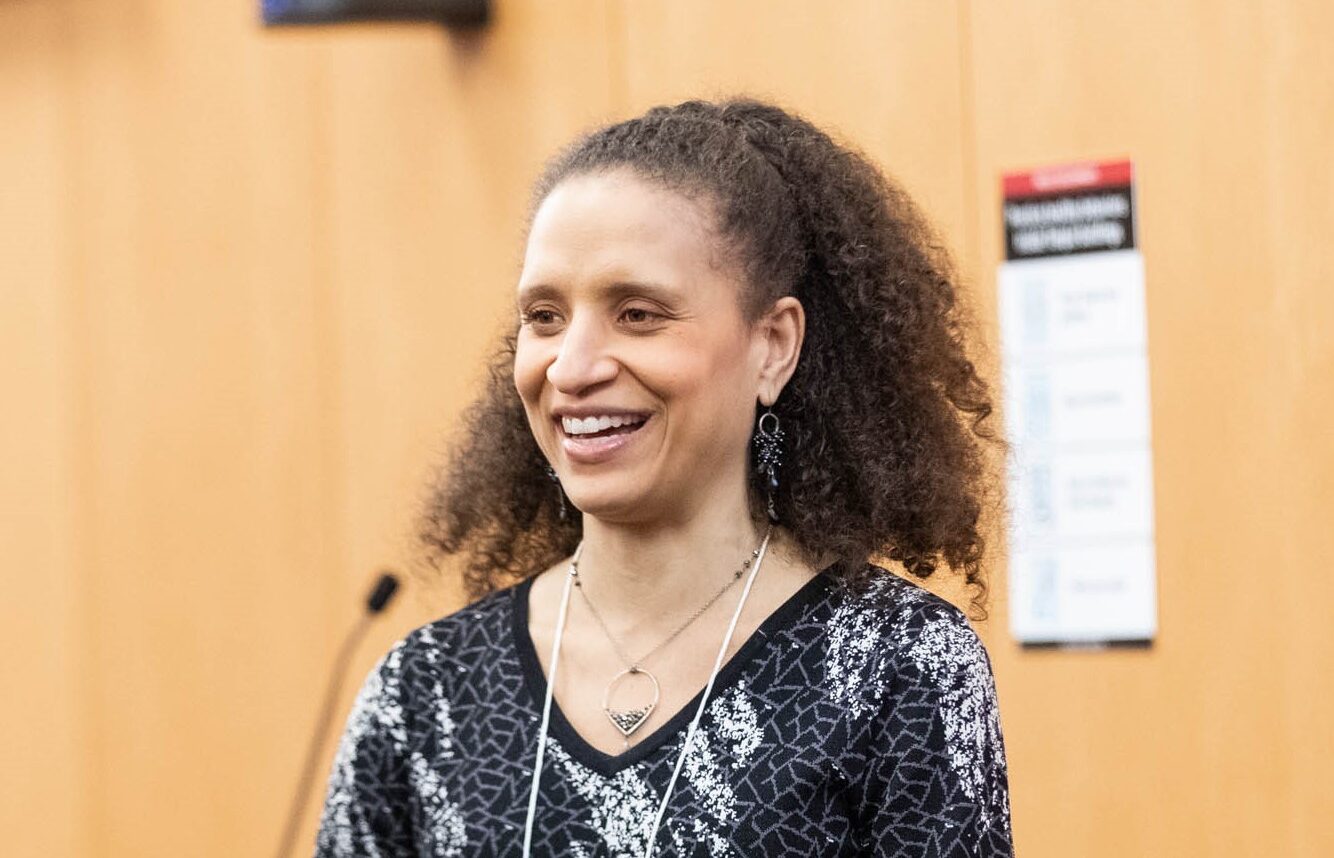 A woman speaks into a microphone at an event.